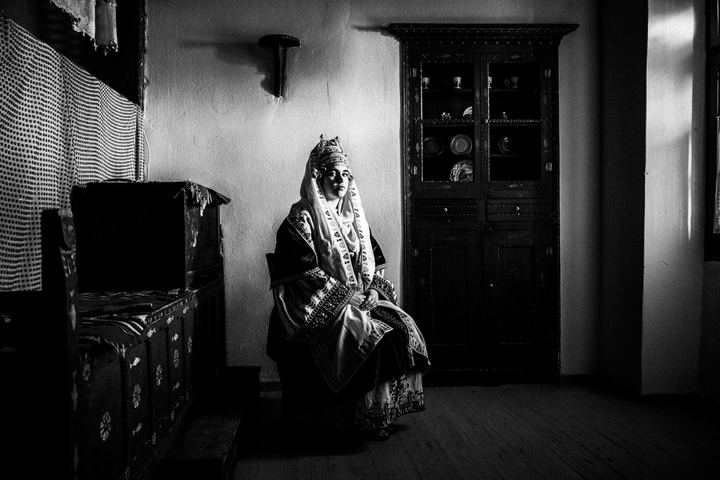 A woman wearing the local bridal costume of Astypalaea, sitting inside a local house