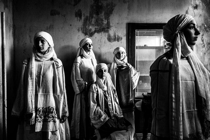 Three women wearing the local costumes of Kallimasia in Chios, inside an old abandoned local house.