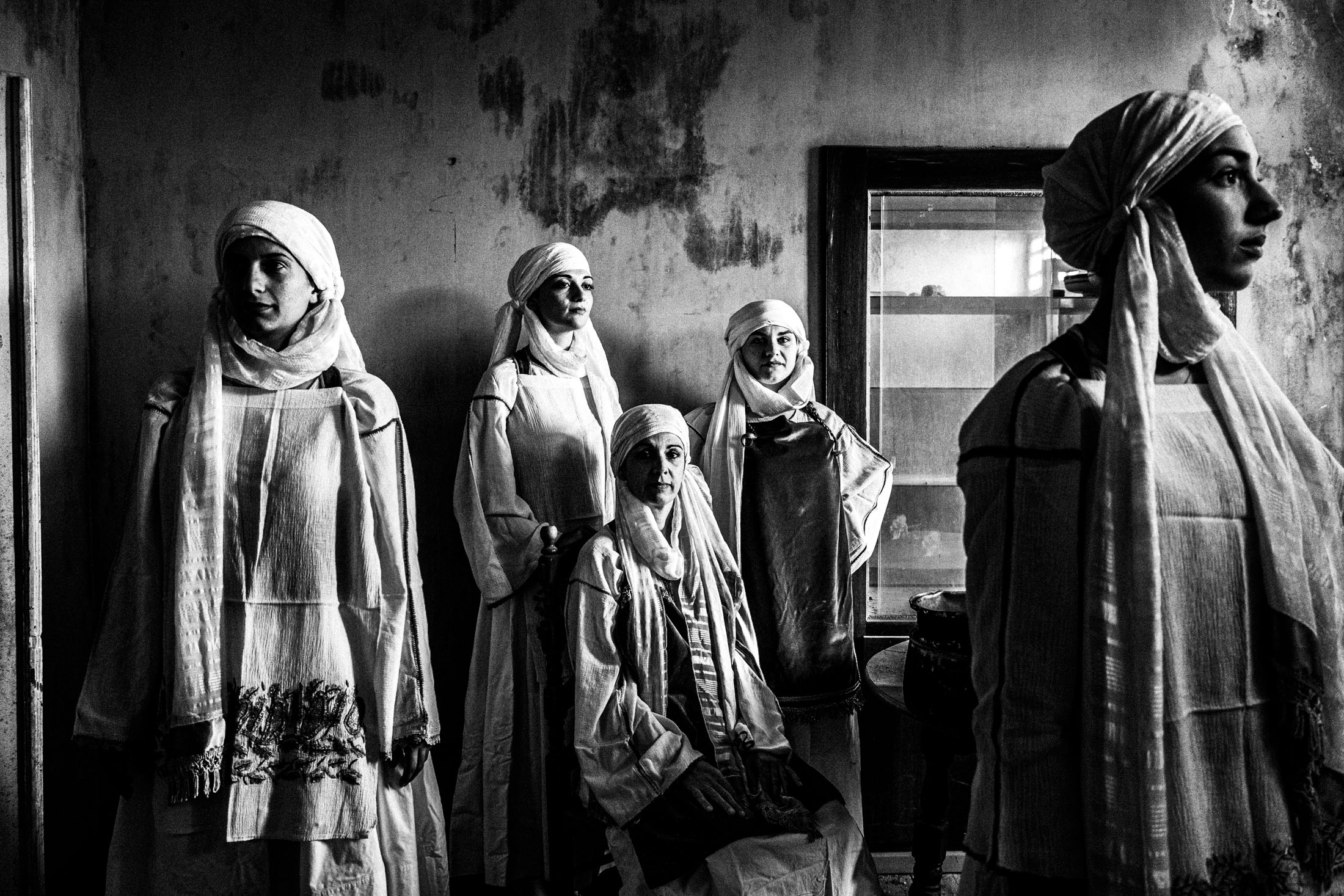 Three women wearing the local costumes of Kallimasia in Chios, inside an old abandoned local house.