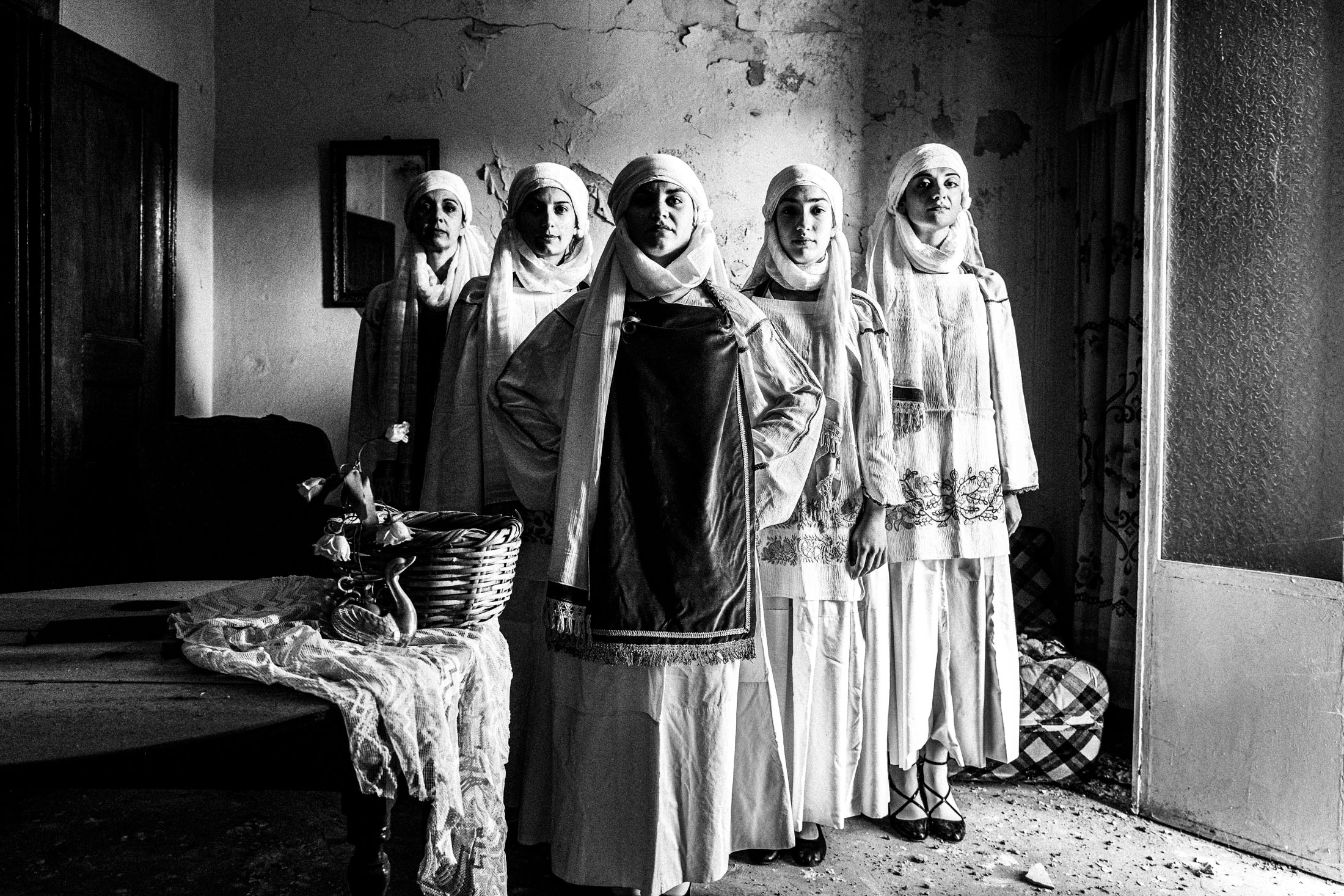 Five women wearing the local costumes of Kallimasia standing in formation inside a local house