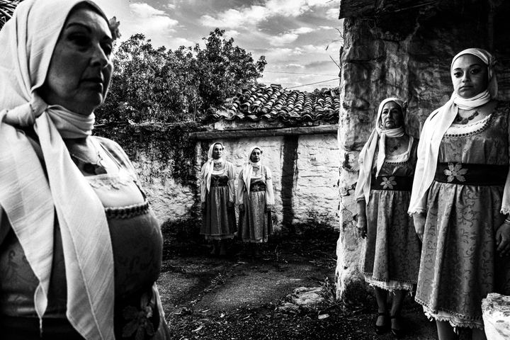Five women standing in a backyard, wearing the local urban dresses of Vassileoniko in Chios