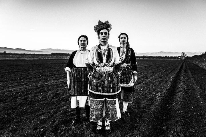 Three women wearing the local dresses of the villages of the valley of Naoussa, standing in a ploughed local field