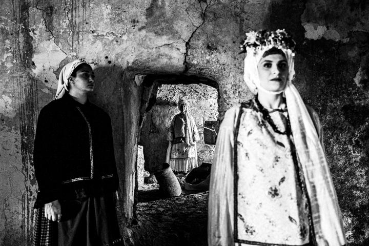 Three women wearing the local costumes of Agios Georgios Sykoussis in Chios, standing inside a local house.
