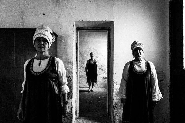 Women wearing the local costumes of Neochori standing inside a local abandoned house