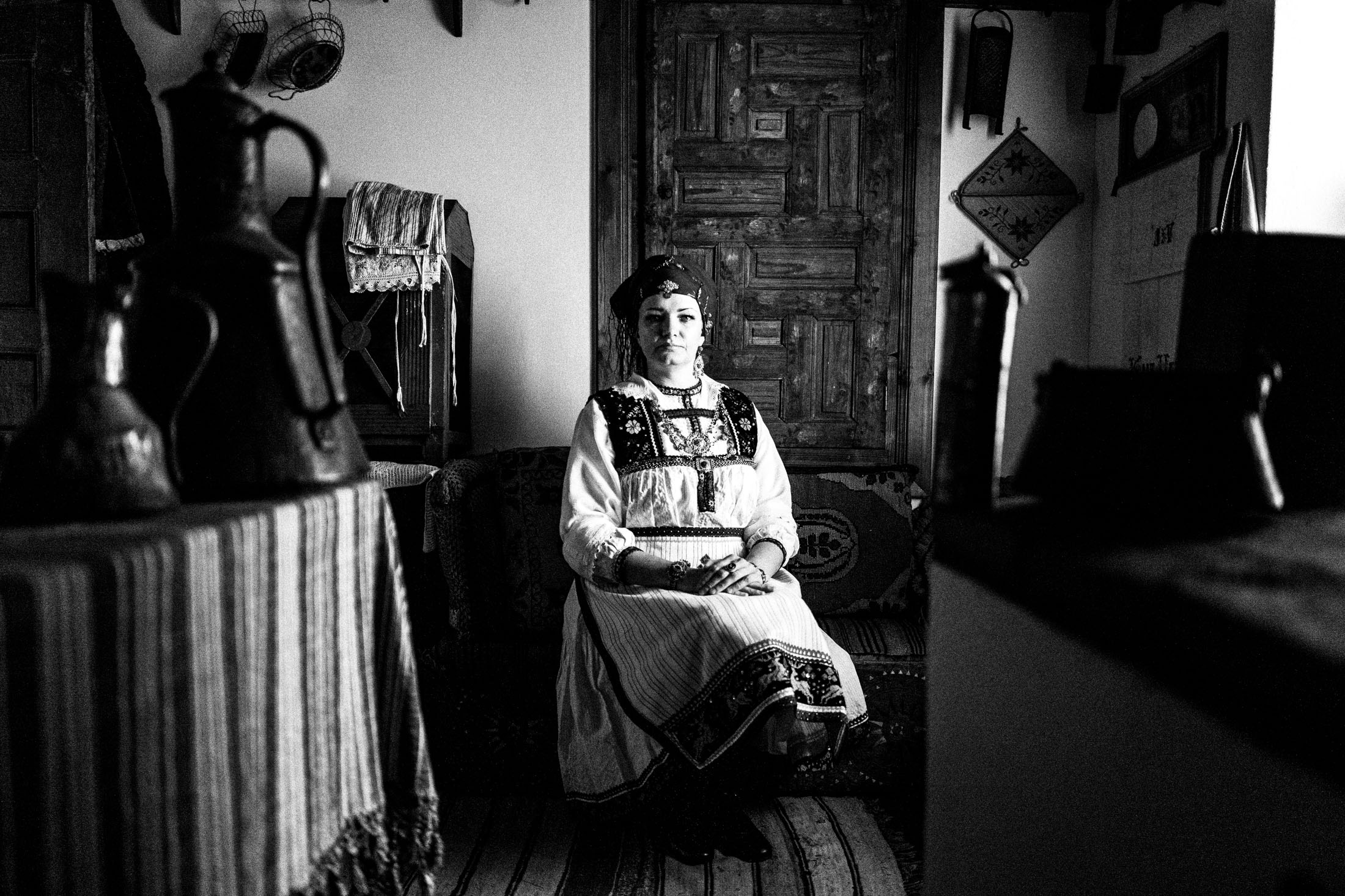 A woman wearing the local costume of Tsartsampas, sitting inside a traditional mansion in Siatista