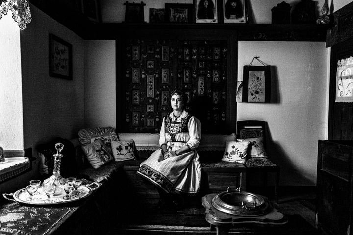 A woman wearing the local costume of Tsartsampas, sitting inside a traditional mansion in Siatista