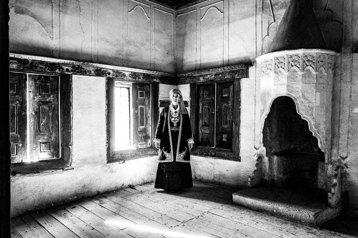 A woman wearing the urban dress of Kozani, standing inside a traditional mansion in Siatista
