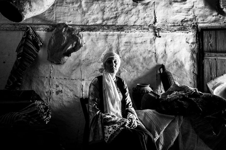 A woman wearing the local costume of Vamvakou, sitting inside a local warehouse