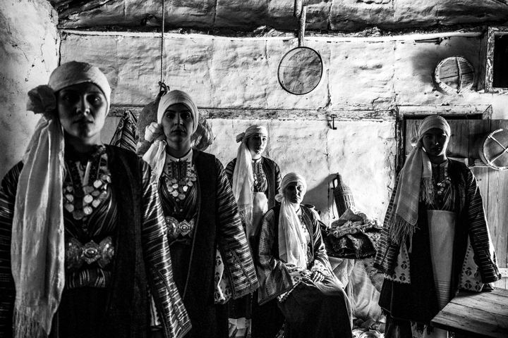 Women wearing the local costumes of Vamvakou in the Peloponnese, posign inside an old local warehouse