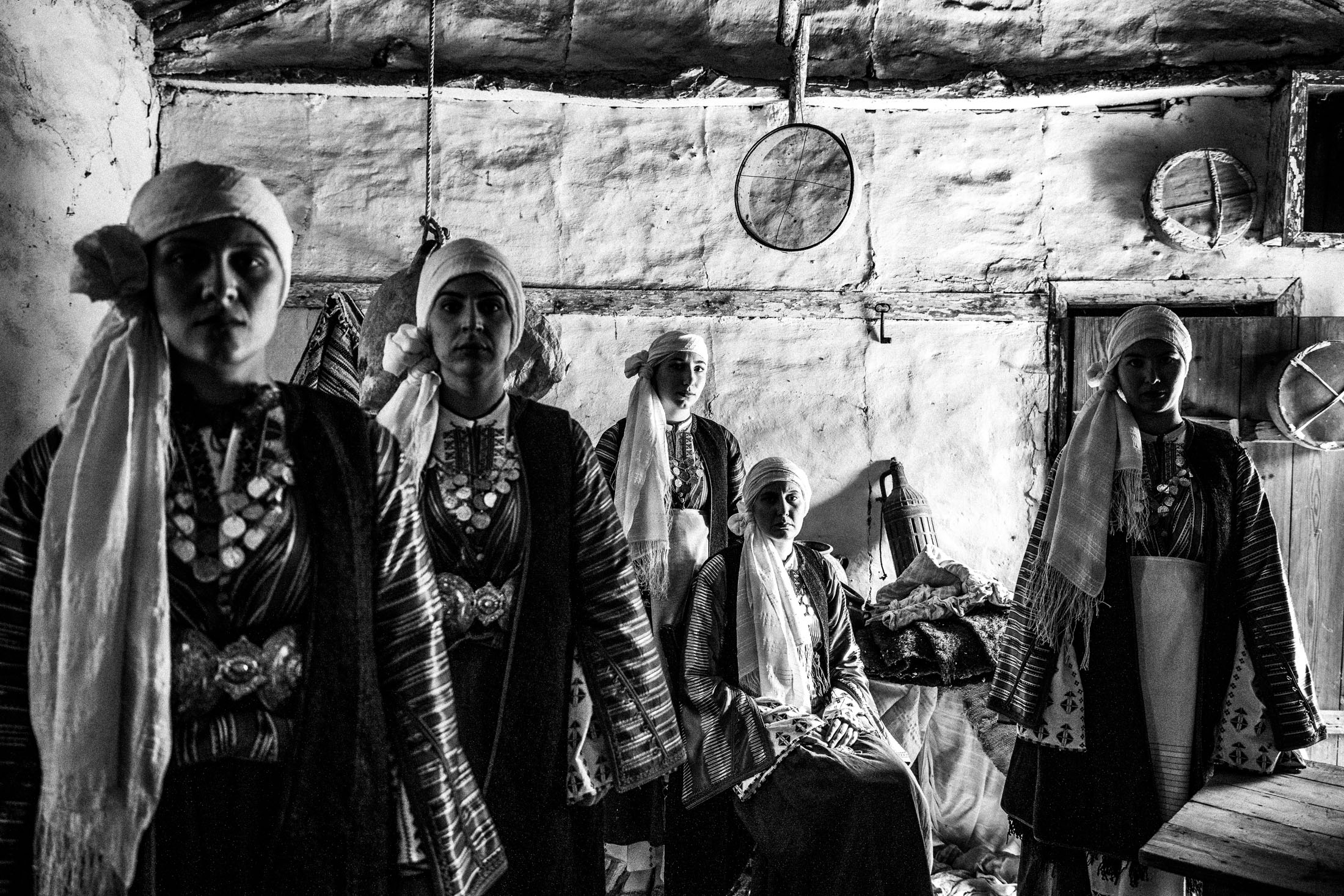 Women wearing the local costumes of Vamvakou in the Peloponnese, posign inside an old local warehouse