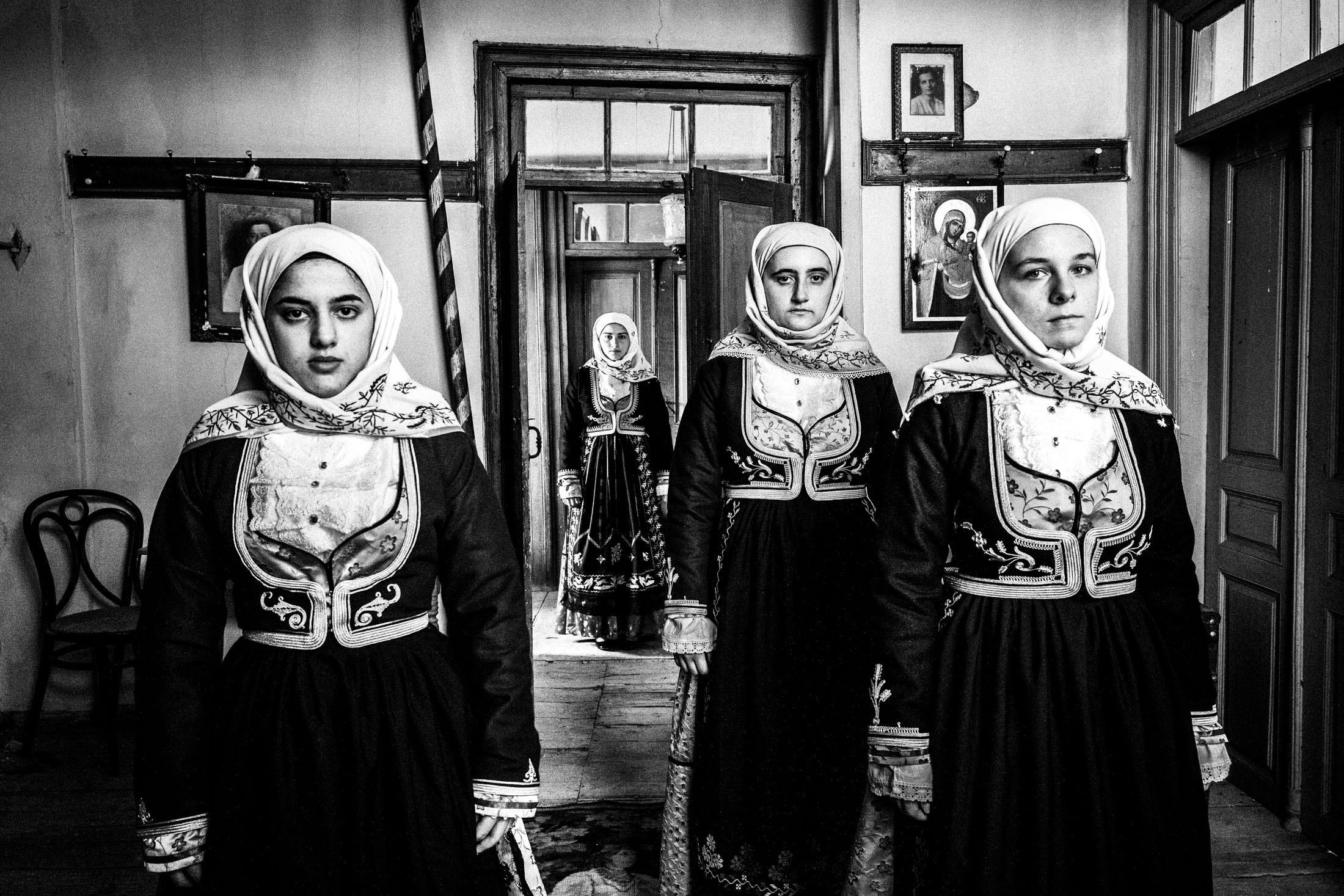 Women wearing the local costumes of Geraki in the Peloponnese, standing inside a local house