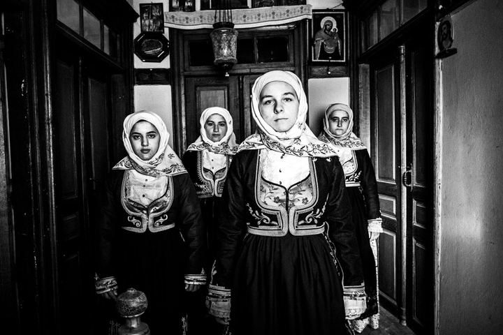 Women wearing the local costumes of Geraki in the Peloponnese, standing inside a local house