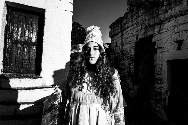 A young women is standing in the village of Thymiana for a close-up portrait on the island of Chios