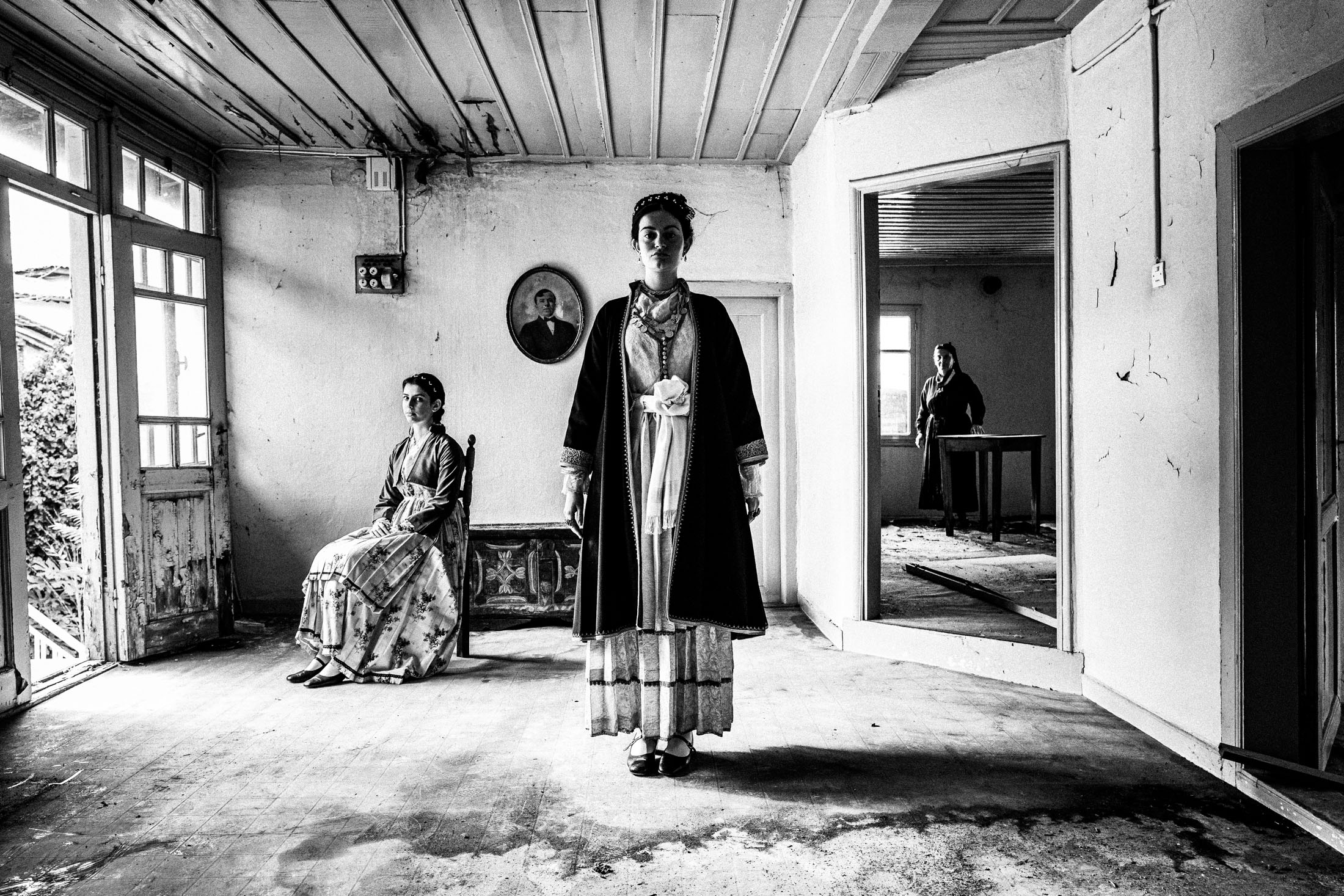 Three women wearing the urban dresses of Veria, Imathia, Macedonia, posing inside a local abandoned house