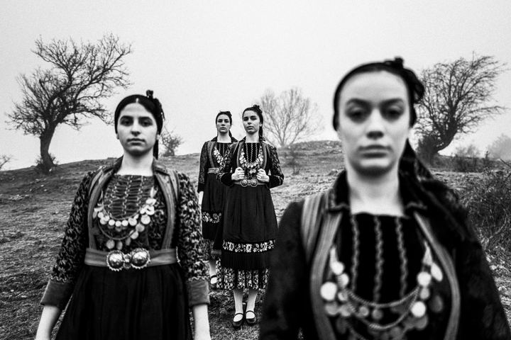Four women wearing the local costumes of Agia Paraskevi (Kerasovo), standing at a misty local hill