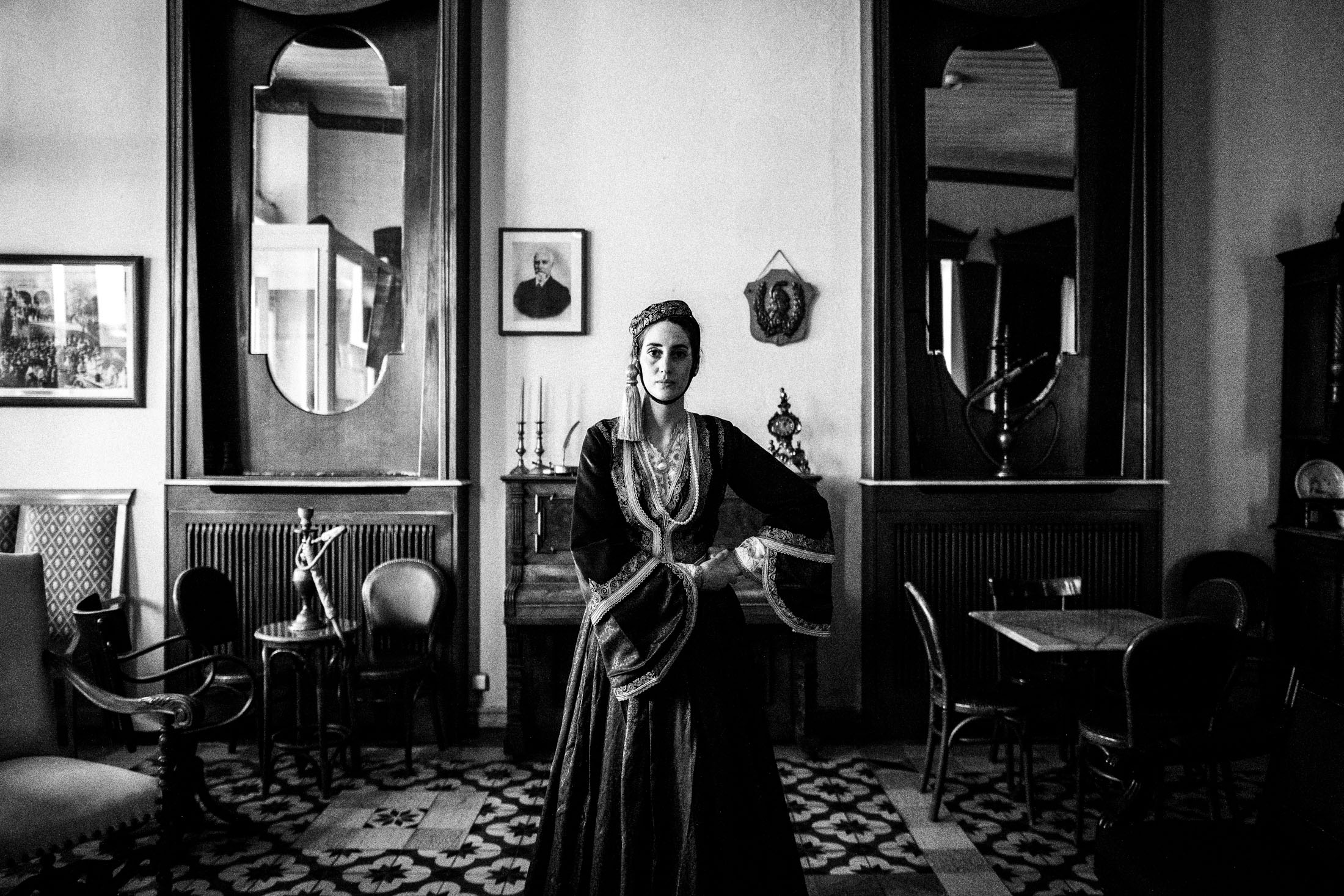 A woman wearing the urban Amalia costume, standing inside a traditional cafe in Tripolis, Peloponnese