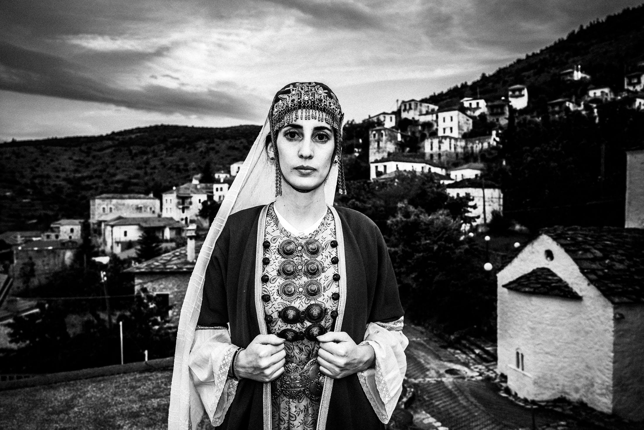 Close-up portrait of a woman on a rooftop, wearing the local dress of Prastos, Arcadia, overlooking the village.