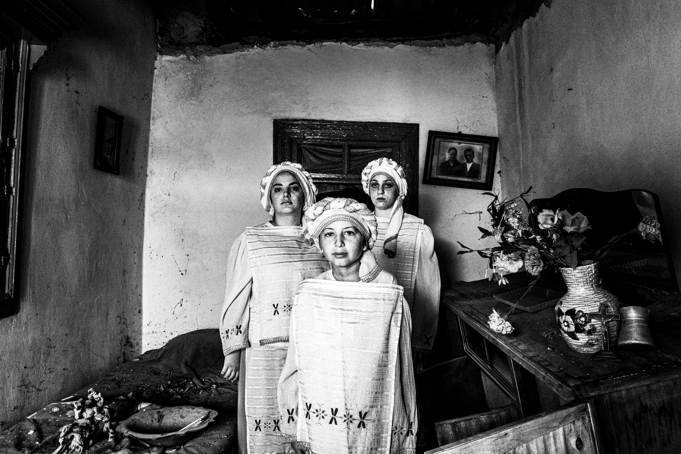 Three young women wearing the local costumes of Dafnonas standing inside an old abandoned local house.