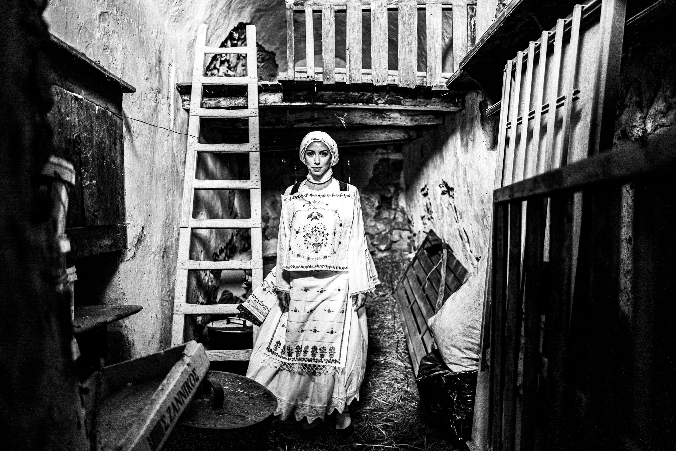 Woman wearing the local costume of Lithi, standing by a ladder inside a local house