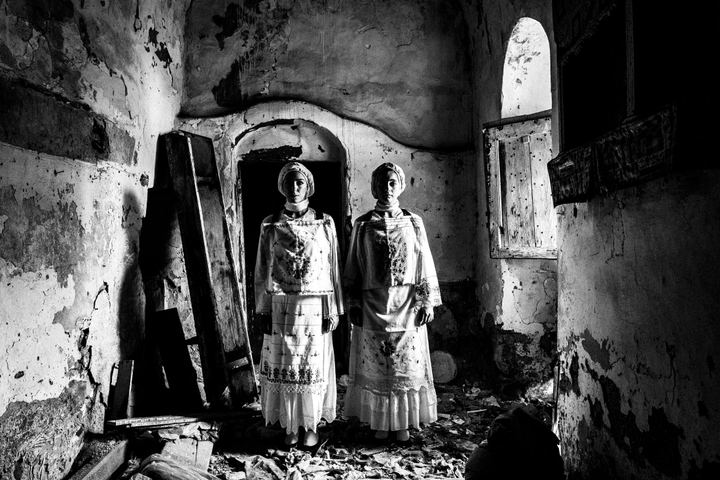 Two women wearing the local costumes of Lithi, standing side by side inside a local house