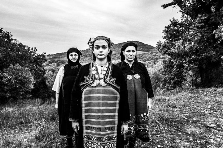 Three women wearing the costumes of Kostellides, stand in formation at a field in Palatitsia, Imathia