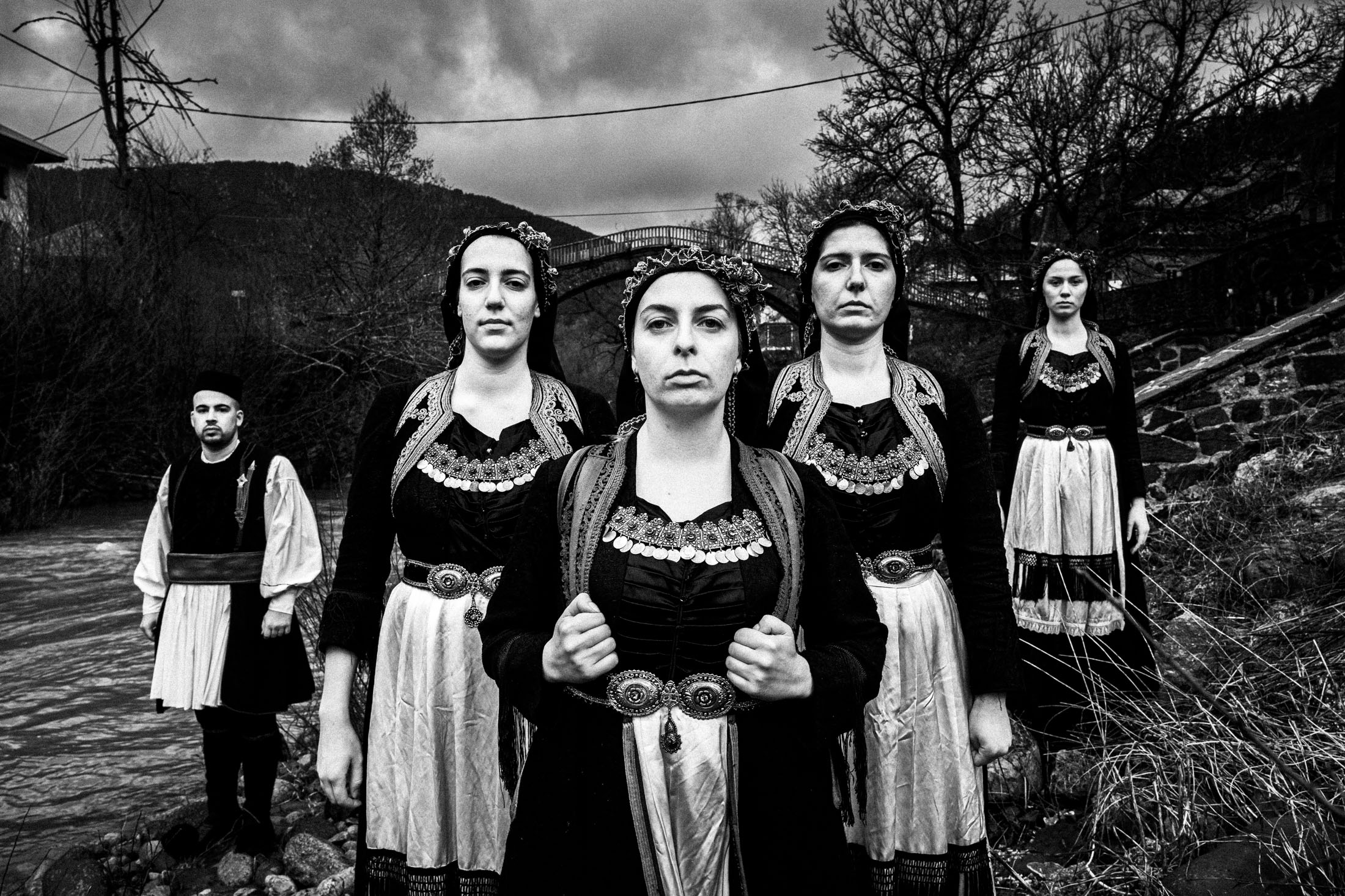 A group wearing the local costumes of Vovoussa, standing by the village's river bank