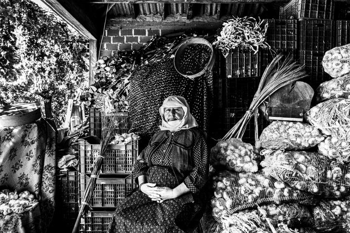 Woman wearing the local costumes of Nea Vyssa in Evros sitting in a garlic pantry