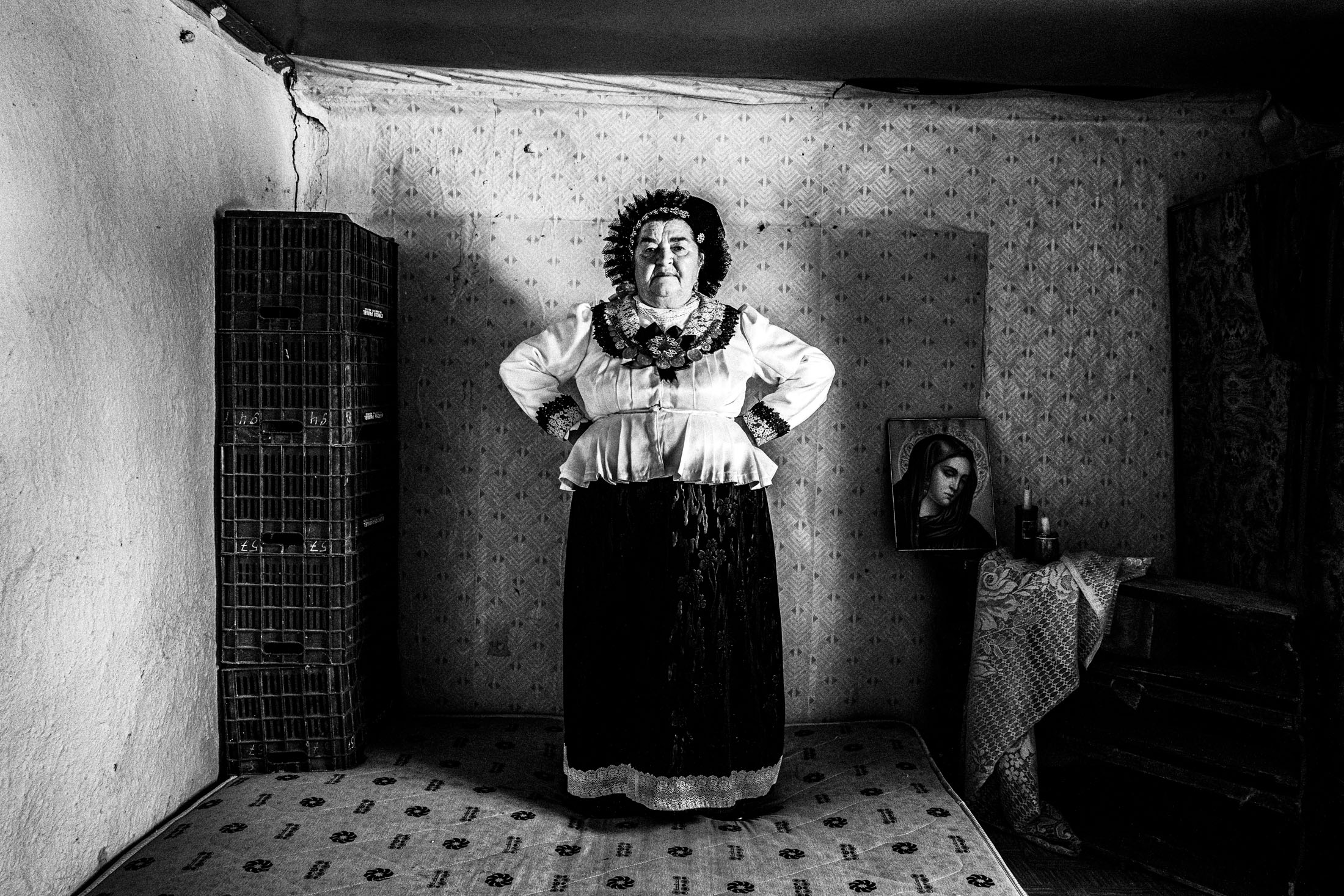 Woman wearing the local costume of Nea Vyssa in Evros standing on a matress in a local home.