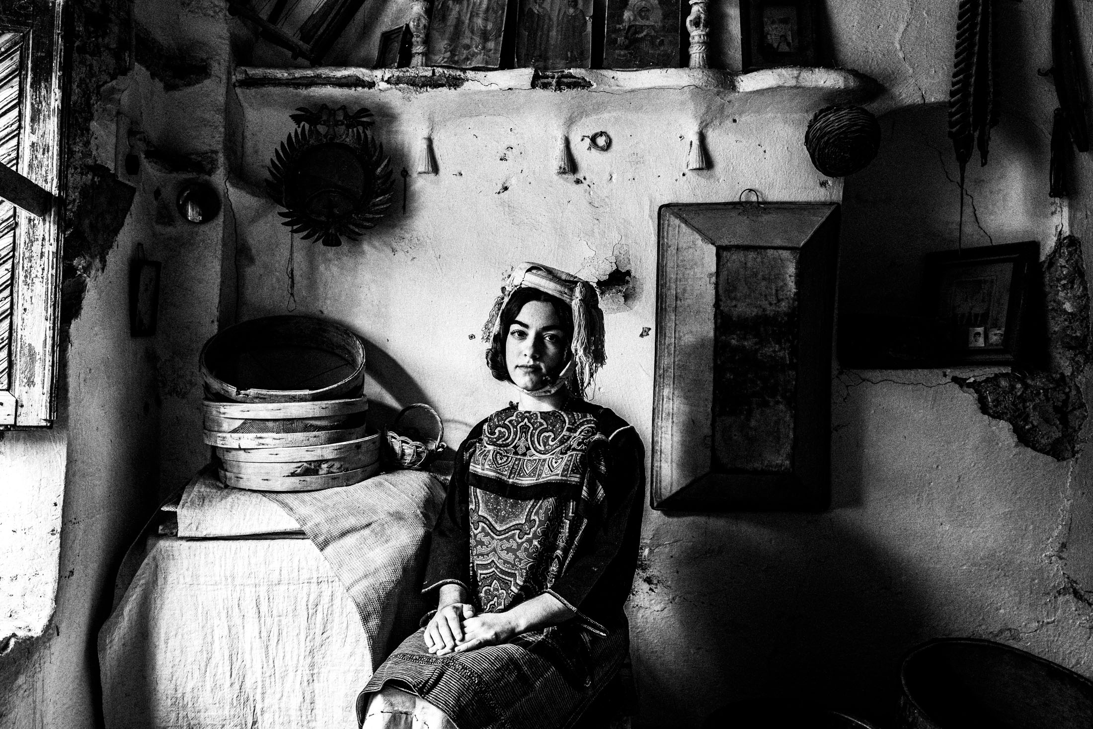 A woman wearing the local costume of Lithi, seated inside a local house by a window