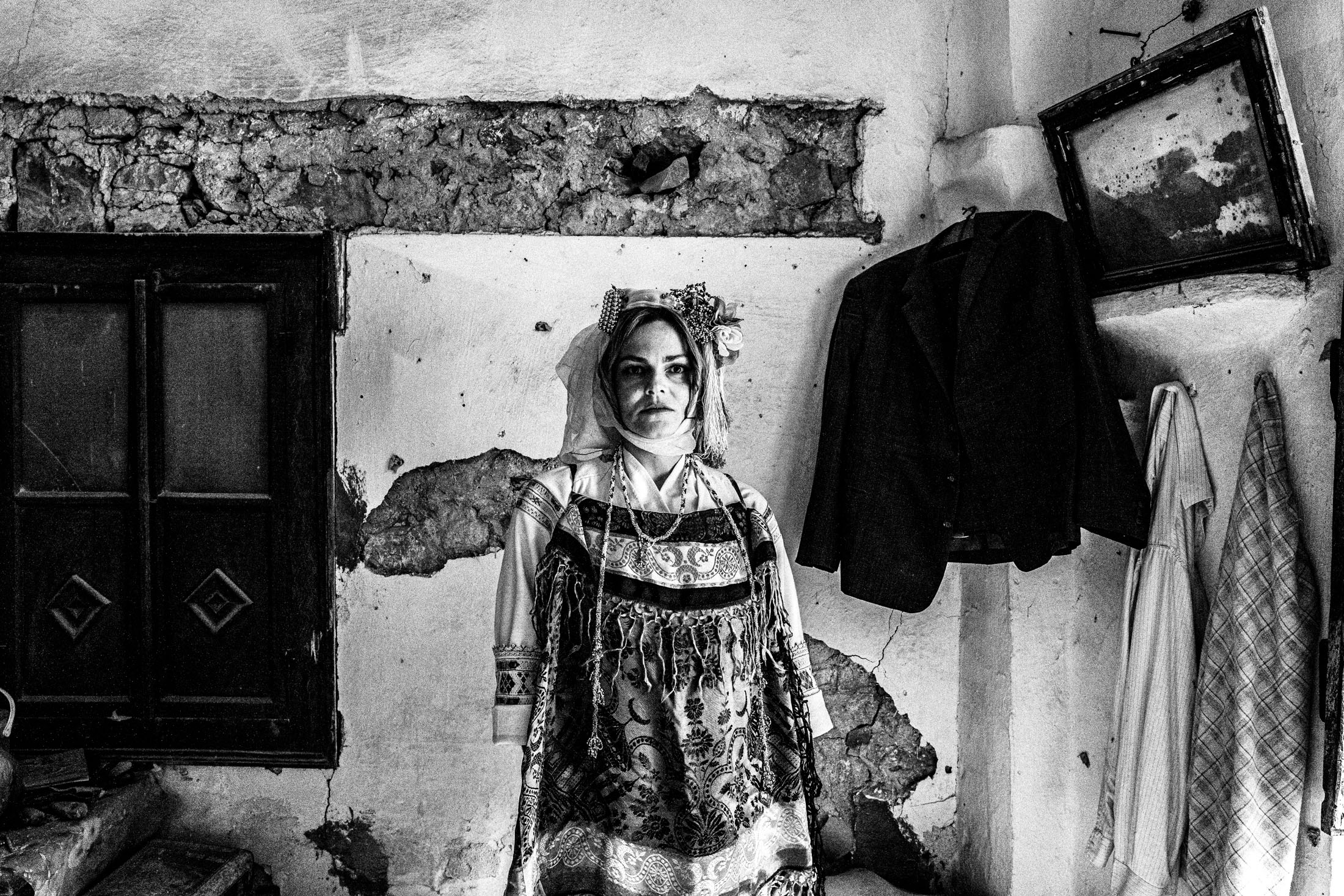 A woman wearing the local costume of Lithi, seated inside a local house by a window
