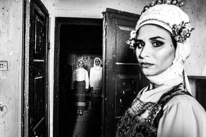 Three women inside an old house, wearing the local dresses of Olympoi, Chios