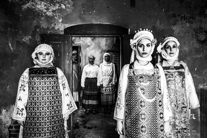 Six women inside an old house, wearing the local dresses of Olympoi, Chios