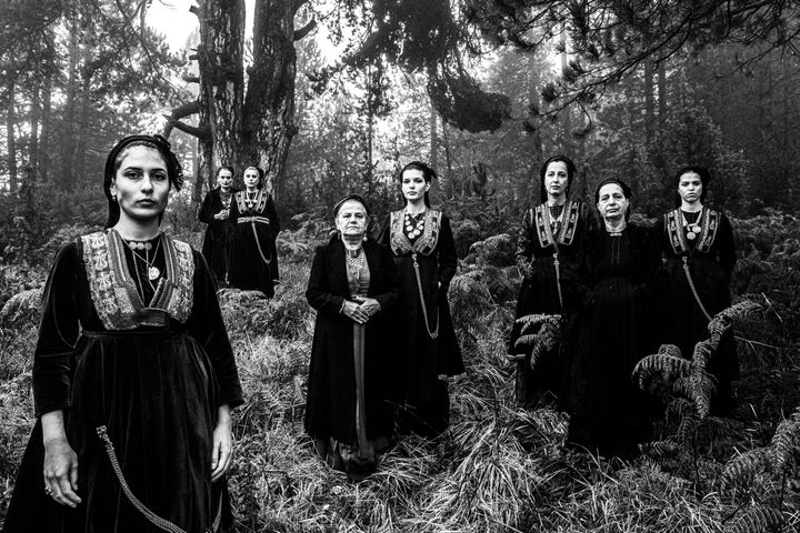 A group of women wearing the costumes of the nomadic group of vlachs, stand in a misty forest in Seli, Imathia