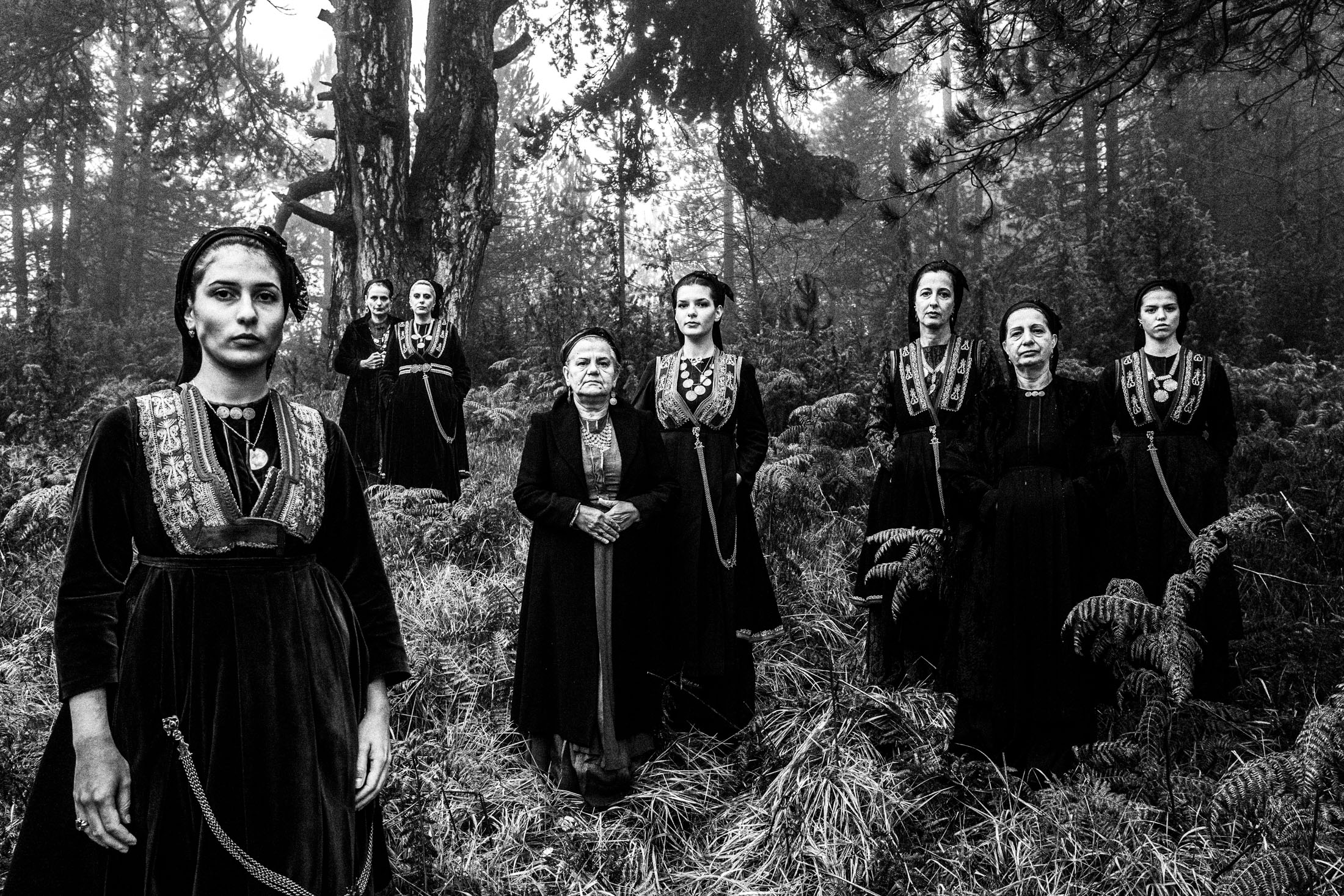 A group of women wearing the costumes of the nomadic group of vlachs, stand in a misty forest in Seli, Imathia