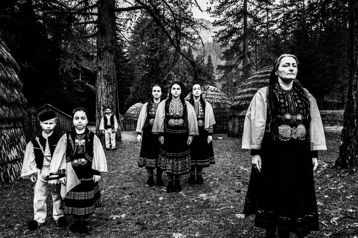 A group of people wearing the costumes of the nomadic grouop of Sarakatsani at Gyftokampos by traditional huts