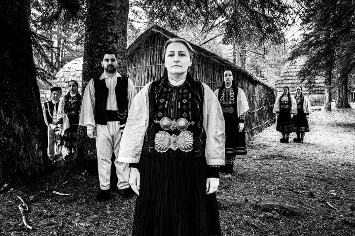 A group of people wearing the costumes of the nomadic grouop of Sarakatsani at Gyftokampos by traditional huts