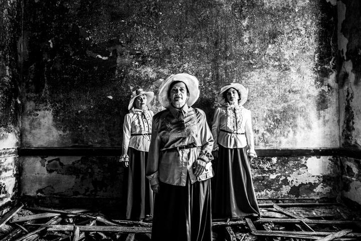 Three women in the local urban dresses of Kofinas in Chios, standing inside the local abandoned leprosarium