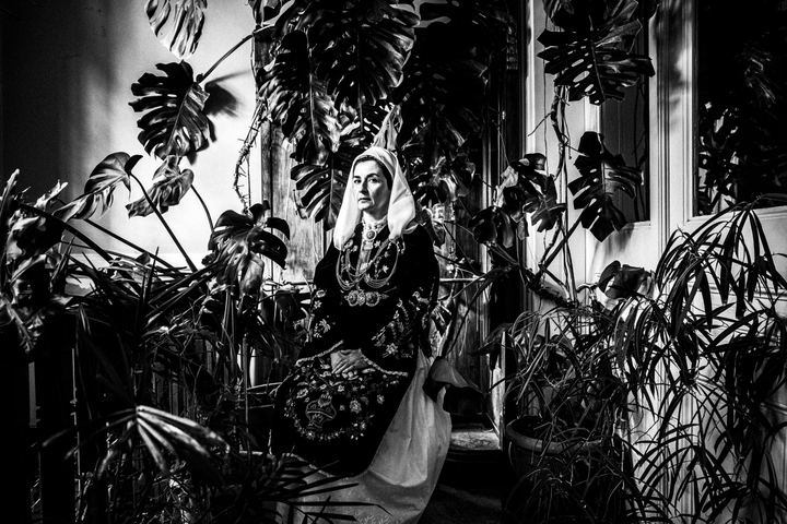 A woman wearing the costume of Martino sitting by a huge monstera plant at a local house
