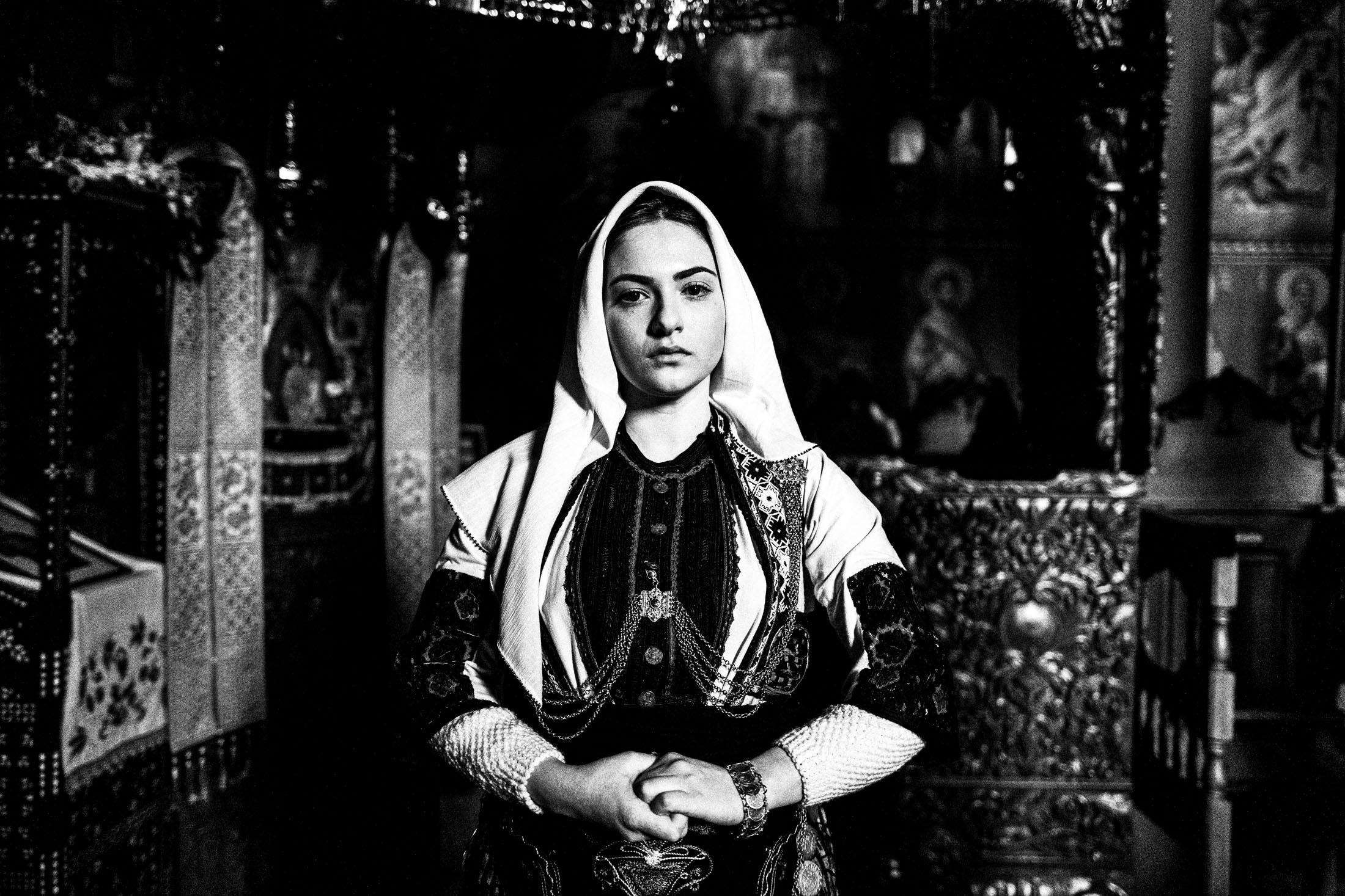 A woman wearing the local costume of Kladorachi in Florina, posing for a close-up portrait inside a local orthodox church