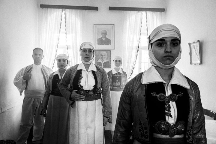 A group of people wearing the costumes of Pogoni, Epirus, inside a local house