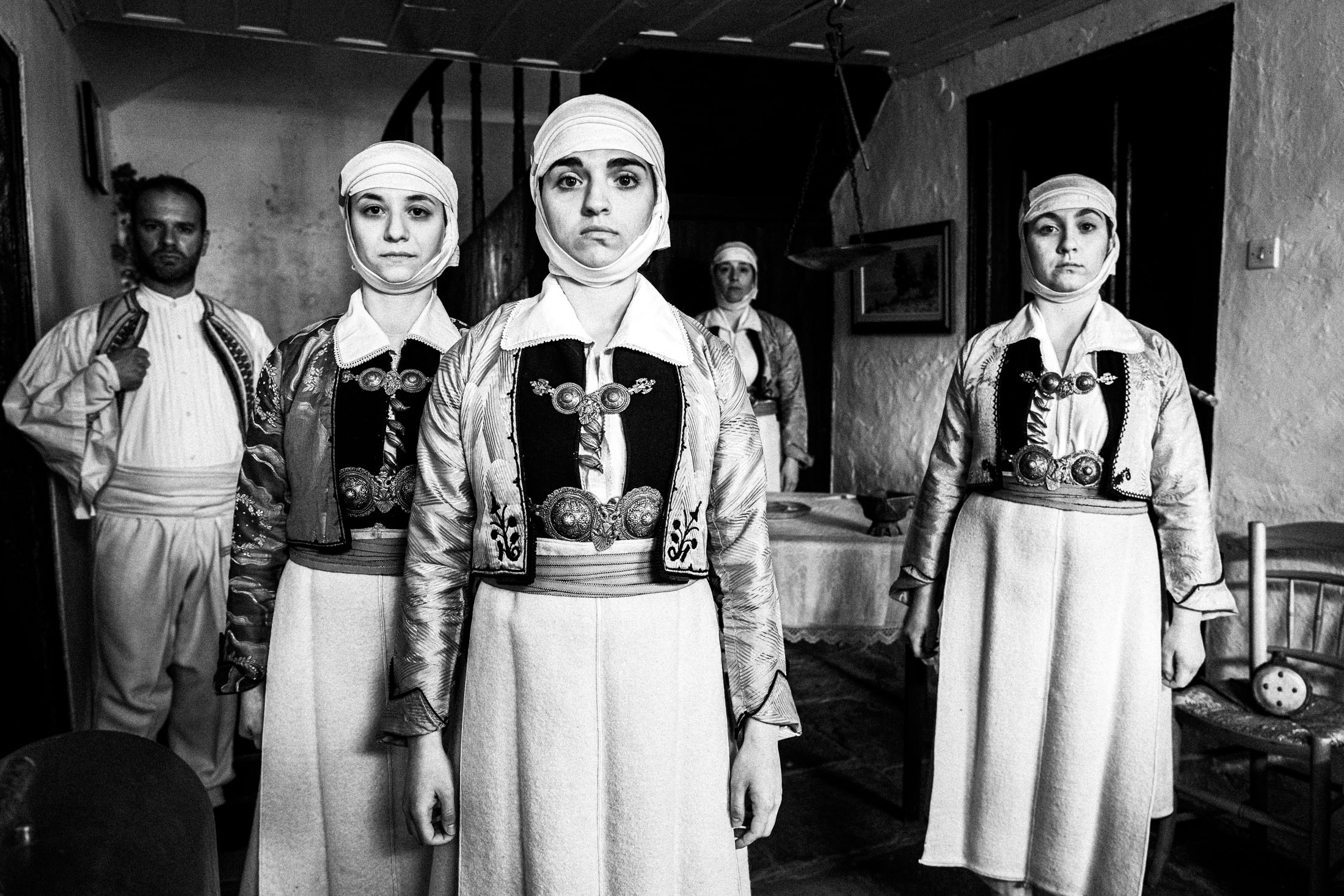 A group of people wearing the costumes of Pogoni, Epirus, inside a local house