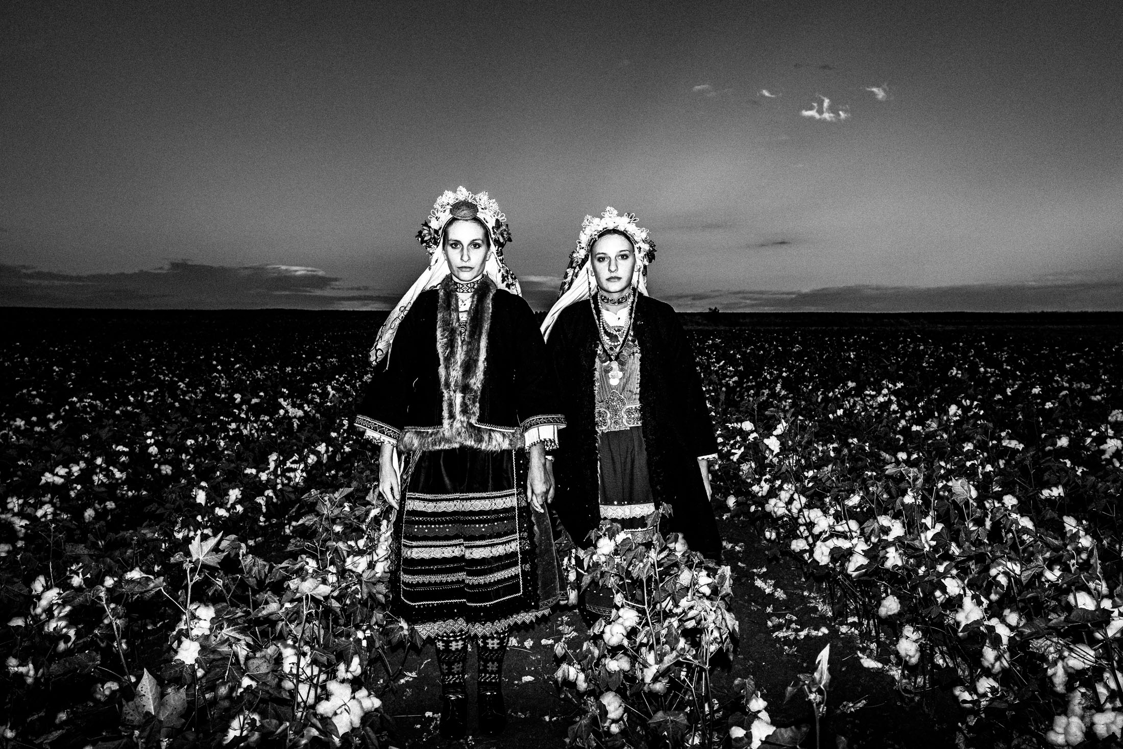 Two young women wearing the local costumes of Vryssi in Evros, standing in a cotton crop.