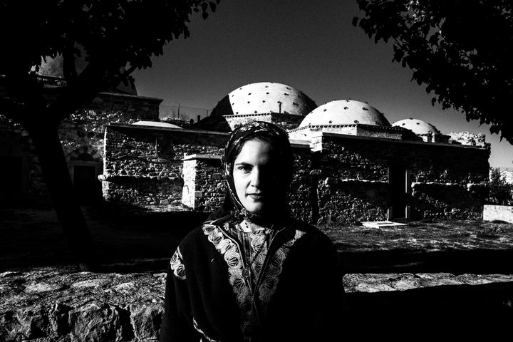A woman wearing the traditional costume of Capadoccia, photographed on the island of Chios, in front of a local mosque