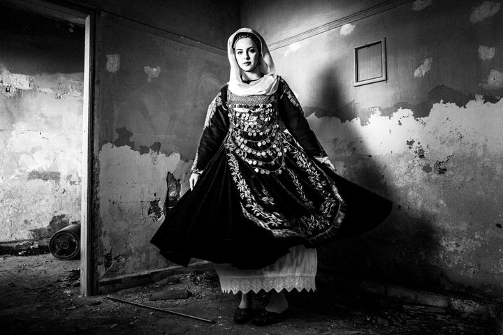 A woman spinning inside a local home, wearing the local costume of Salamina.