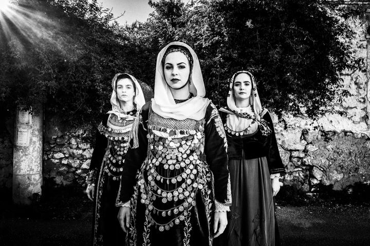 Three women in the local dresses of Salamina, standing in a local alley. Bridal, engagement and everyday dresses.