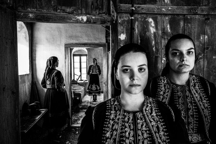 A group of women wearing the local costumes of Filiates in Thesprotia, standing inside a local old abandoned house