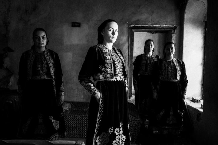 Four women wearing the local costumes of Filiates in Epirus, standing inside a local abandoned house.