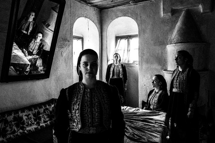 Four women wearing the local costumes of Filiates in Epirus, standing inside a local abandoned house.