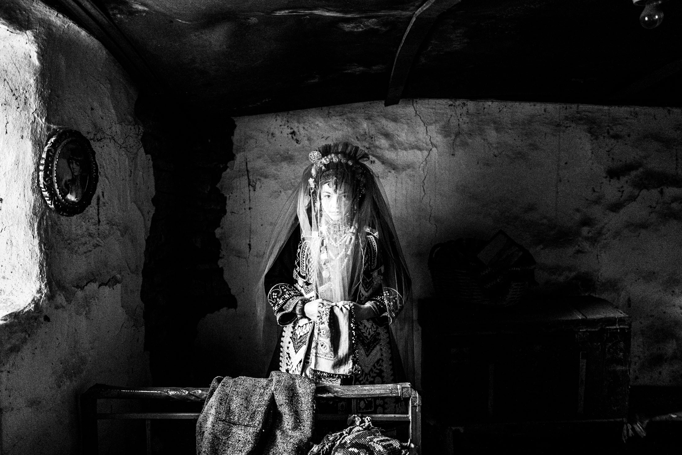 A veiled woman wearing the local bridal costume of Issaakio in Evros, inside a local bedroom
