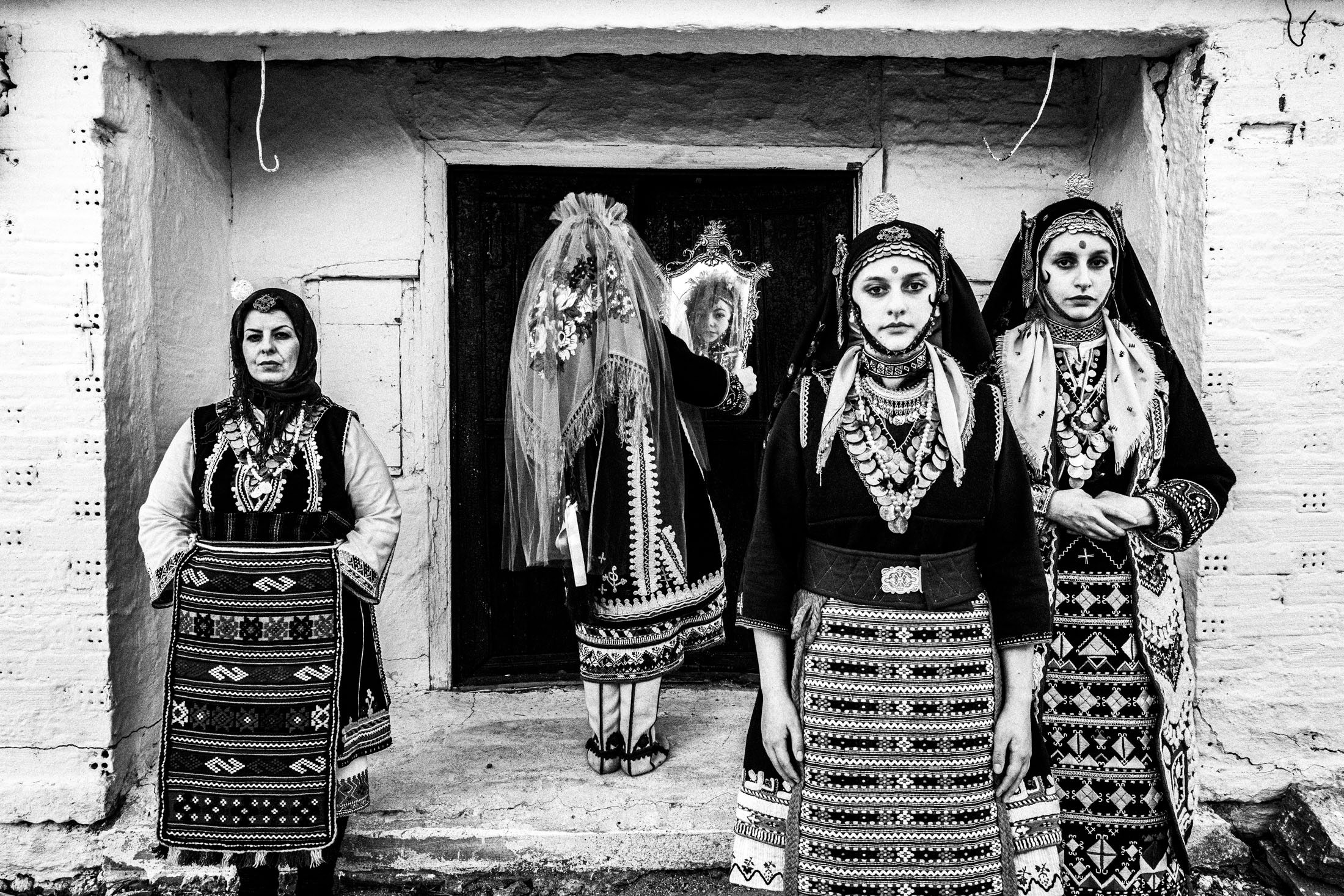 Four women wearing the local costumes of Issaakion in Evros, outside a local traditional house.